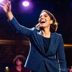 이현정 여성 개그맨의 어려움 - **Prompt:** A dynamic, full-body shot of a female stand-up comedian on a brightly lit stage in a pac...